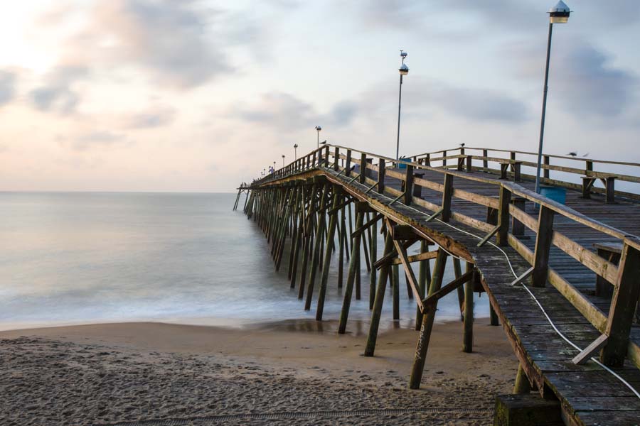 About Our Agency - North Carolina Dock Leading Out the Ocean at Sunrise